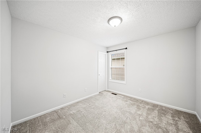 empty room featuring light colored carpet and a textured ceiling