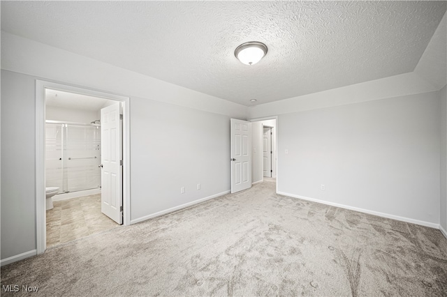 interior space with light colored carpet, a textured ceiling, and ensuite bath