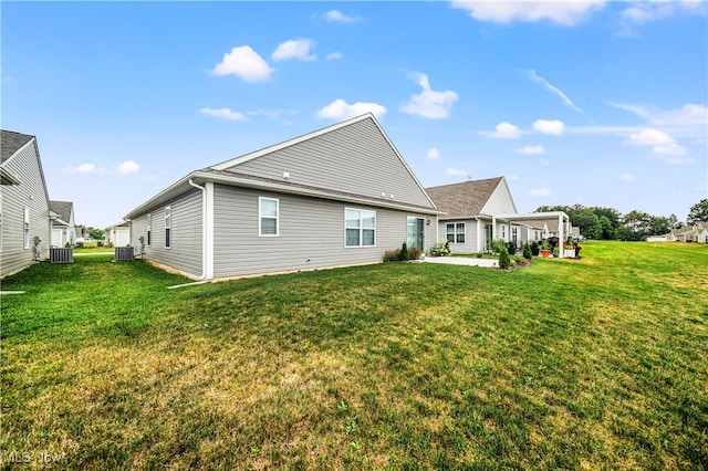 rear view of house featuring central AC unit, a patio, and a lawn