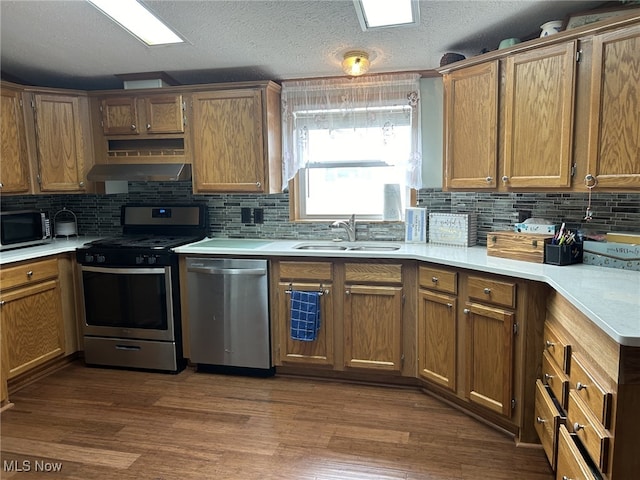 kitchen featuring dark wood-type flooring, backsplash, appliances with stainless steel finishes, and sink