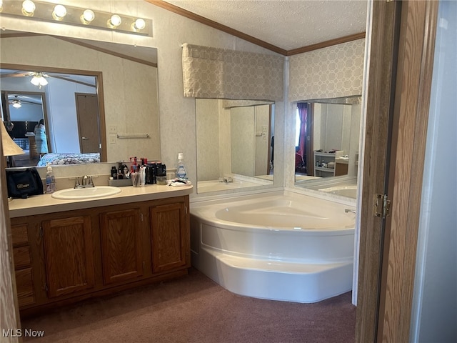 bathroom with vaulted ceiling, a textured ceiling, ornamental molding, vanity, and a tub