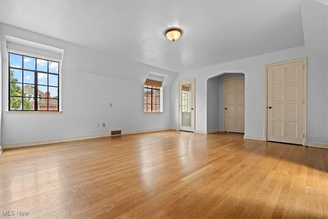 unfurnished room featuring arched walkways, baseboards, visible vents, and light wood finished floors