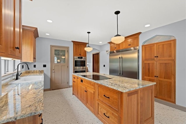 kitchen featuring light stone countertops, stainless steel appliances, a sink, a center island, and brown cabinets