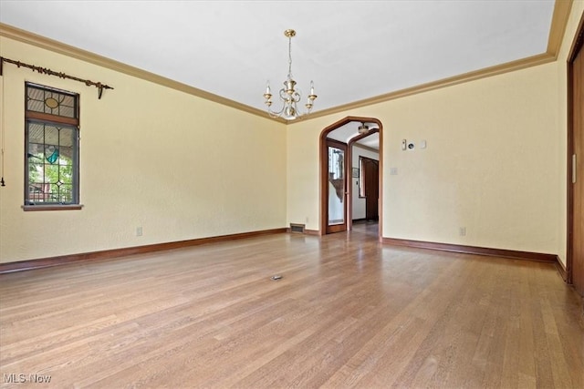 unfurnished room with a chandelier, arched walkways, wood finished floors, and baseboards