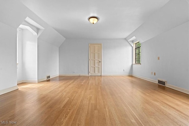 bonus room with light wood-type flooring, visible vents, and vaulted ceiling