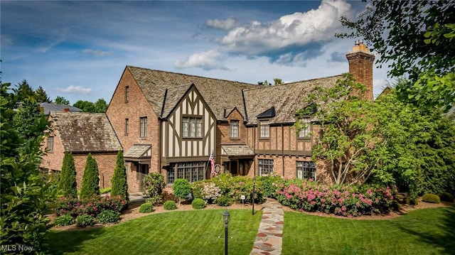 exterior space with brick siding, a chimney, a front lawn, and stucco siding