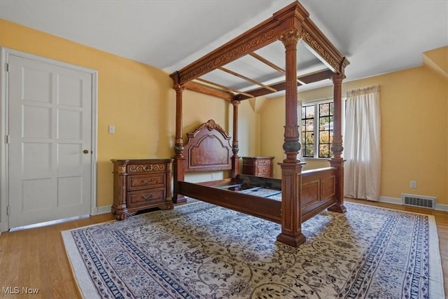 bedroom featuring ornate columns, baseboards, visible vents, and wood finished floors