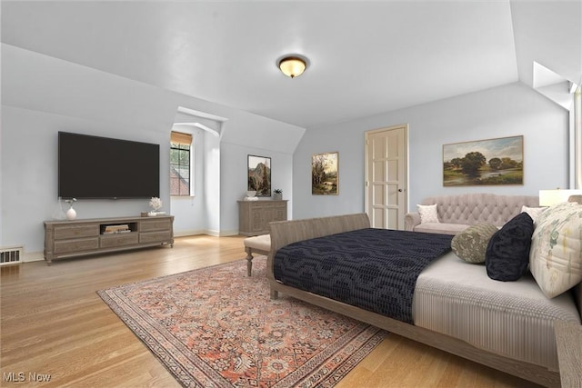 bedroom featuring visible vents, vaulted ceiling, and wood finished floors