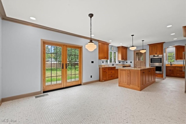 kitchen featuring baseboards, visible vents, brown cabinetry, stainless steel double oven, and a sink