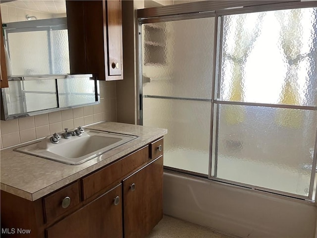 bathroom featuring combined bath / shower with glass door, backsplash, and vanity