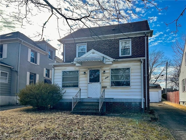 view of front of home with a garage, an outbuilding, brick siding, and fence