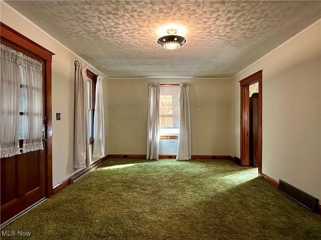 spare room featuring carpet floors, baseboards, visible vents, and ornamental molding