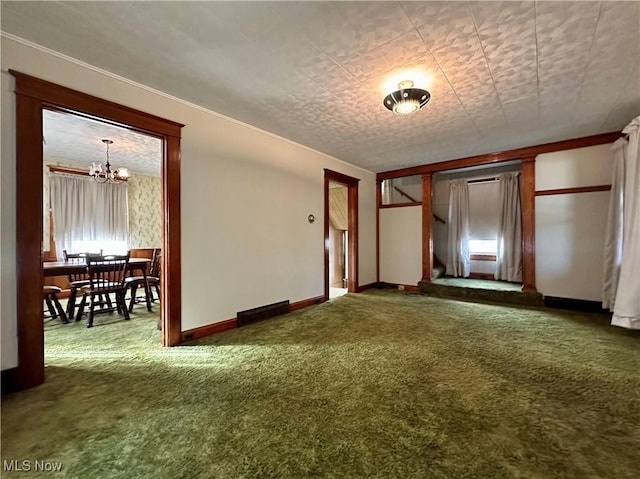 empty room with carpet floors, an inviting chandelier, visible vents, and baseboards