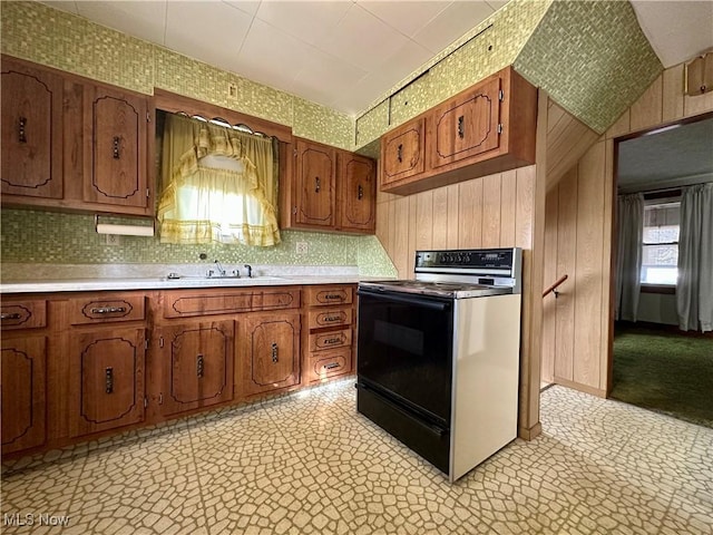 kitchen with brown cabinetry, light countertops, electric range, and light floors