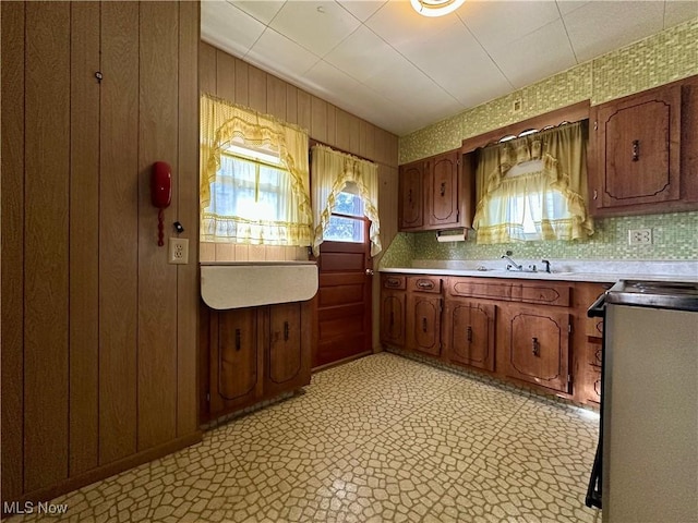 kitchen with a healthy amount of sunlight, light floors, stove, and a sink