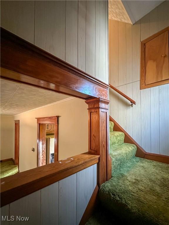 stairway with lofted ceiling and wooden walls