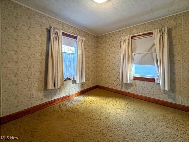 empty room featuring wallpapered walls, carpet, and baseboards