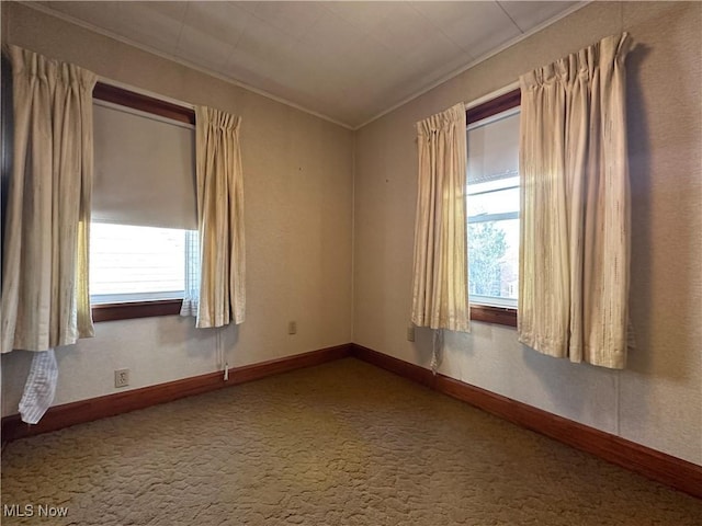 unfurnished room with carpet, crown molding, baseboards, and a wealth of natural light