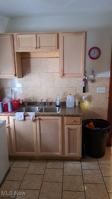 kitchen with dark stone counters, light tile patterned flooring, tasteful backsplash, and sink