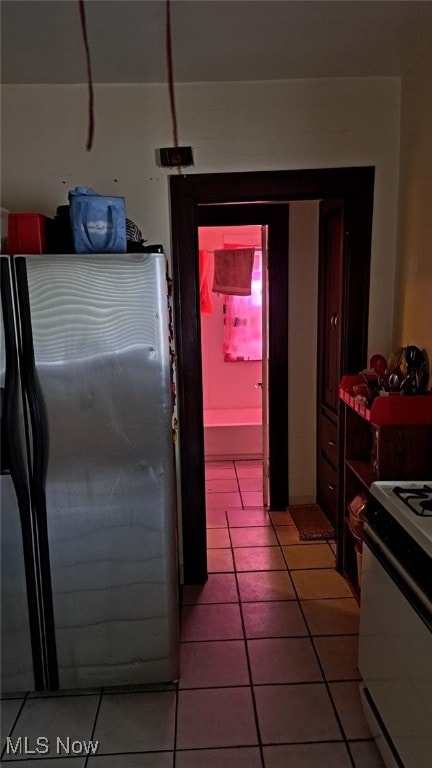 kitchen with white range with electric stovetop, tile patterned floors, and stainless steel fridge