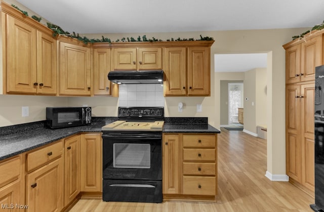 kitchen featuring dark stone counters, electric range, backsplash, and light wood-type flooring