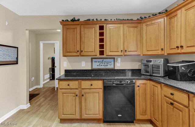 kitchen with black dishwasher, dark stone countertops, and light wood-type flooring