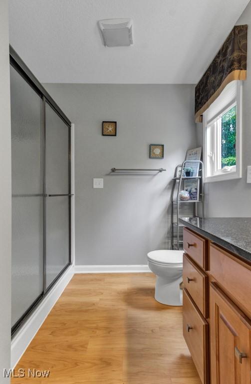 bathroom featuring vanity, toilet, a shower with door, and hardwood / wood-style flooring