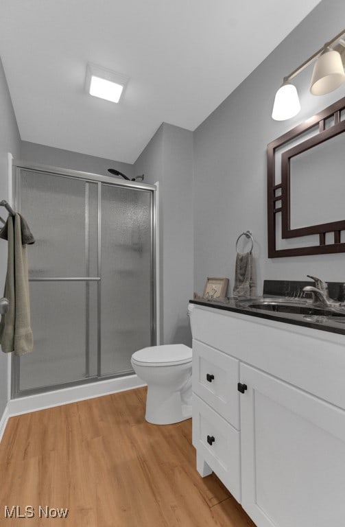 bathroom featuring vanity, walk in shower, toilet, and hardwood / wood-style floors