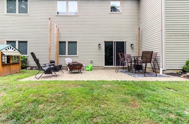 rear view of house featuring a patio area, a yard, and a fire pit