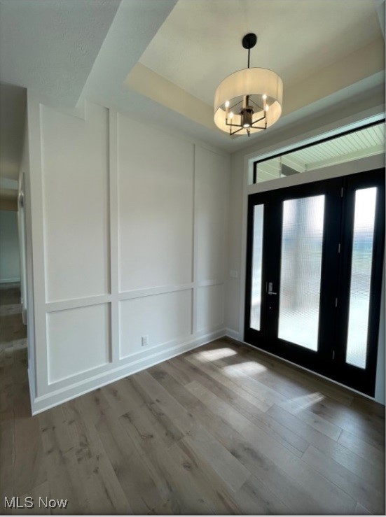 empty room featuring a notable chandelier, hardwood / wood-style floors, and a tray ceiling