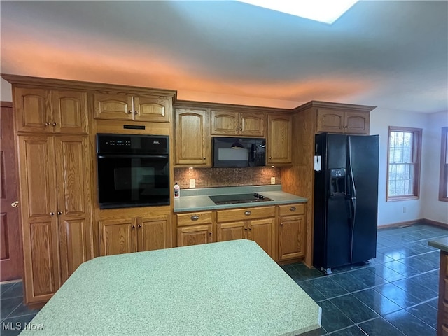 kitchen with backsplash, dark tile patterned floors, and black appliances