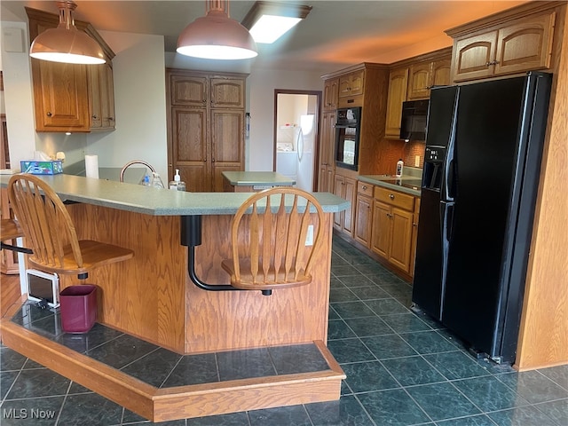 kitchen with black appliances, a kitchen bar, kitchen peninsula, and dark tile patterned flooring