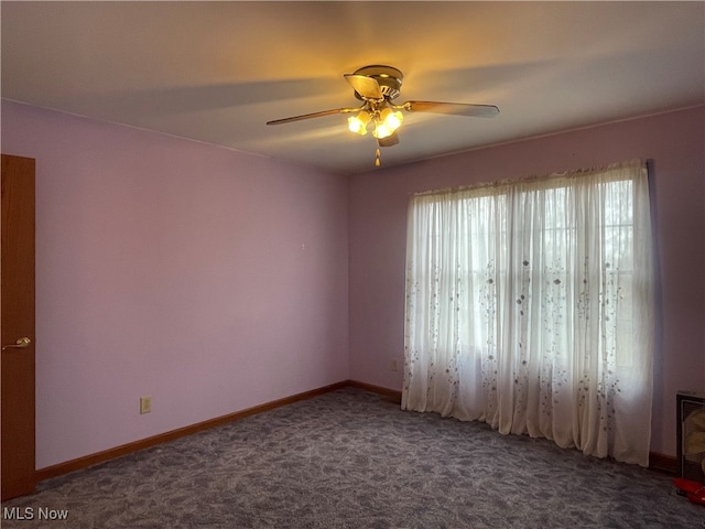 spare room featuring ceiling fan and dark colored carpet