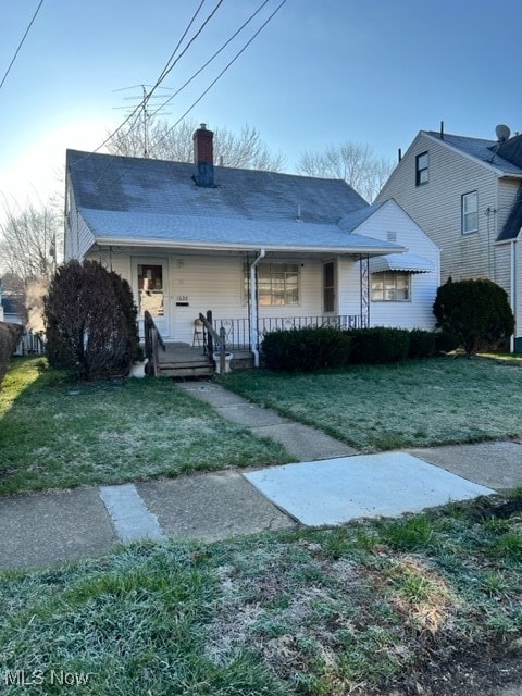 rear view of property featuring covered porch and a yard