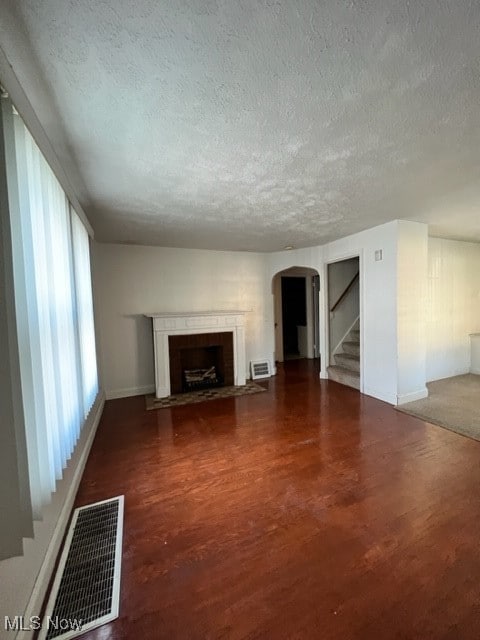 unfurnished living room with a textured ceiling, a fireplace, and hardwood / wood-style floors