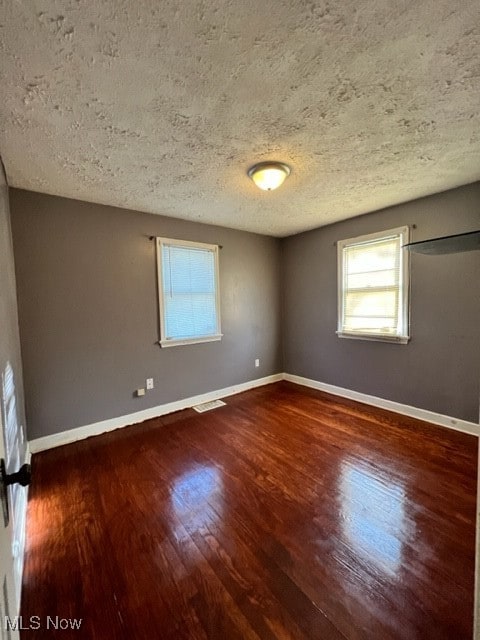 spare room featuring hardwood / wood-style flooring and a textured ceiling