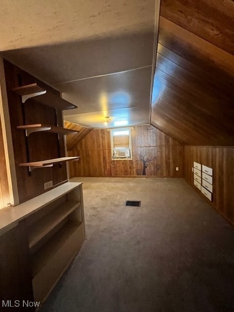 additional living space with wood walls, lofted ceiling, and carpet floors