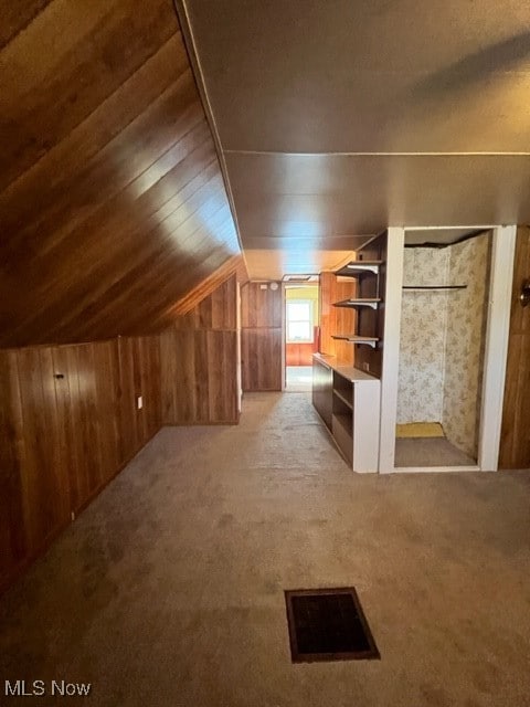 bonus room featuring wooden walls, vaulted ceiling, and light colored carpet