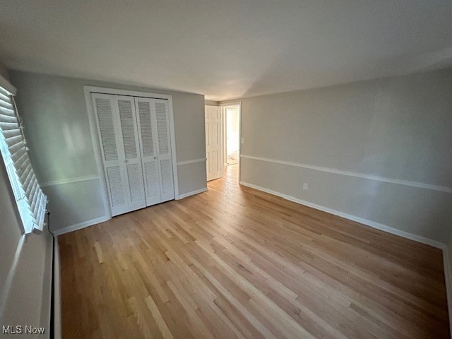 unfurnished bedroom featuring light hardwood / wood-style flooring and a closet