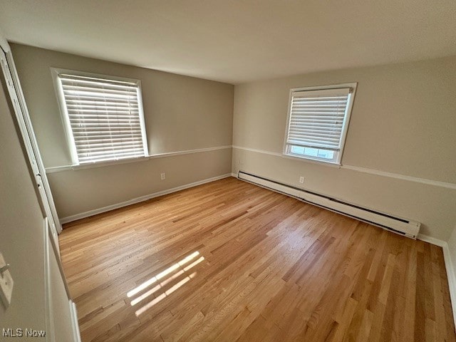 unfurnished room with light hardwood / wood-style flooring and baseboard heating