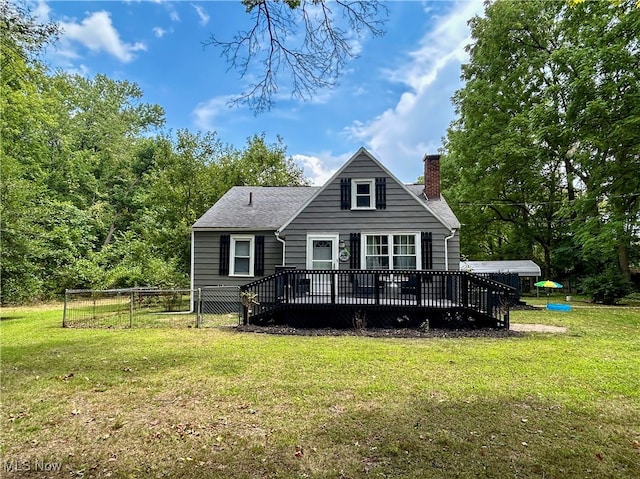 rear view of house featuring a lawn and a deck