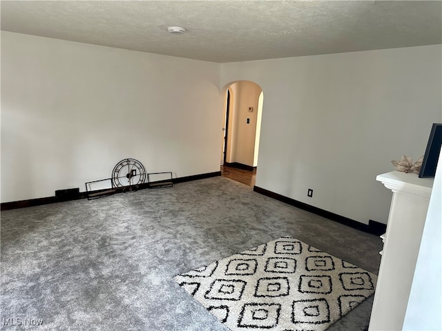 empty room with a textured ceiling and dark carpet