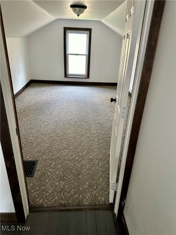 additional living space featuring lofted ceiling and dark carpet