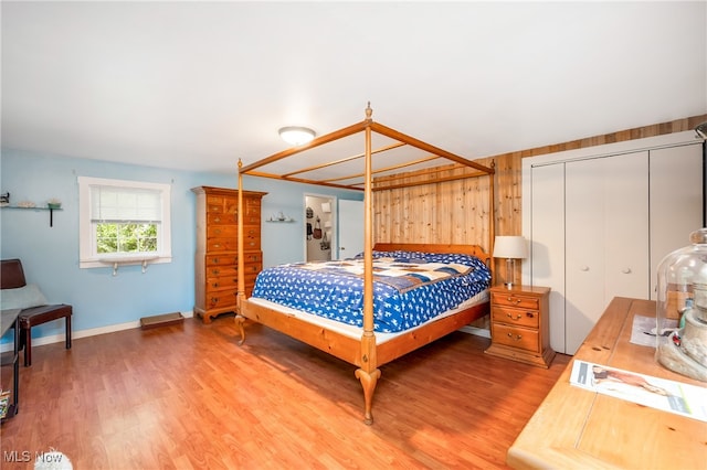 bedroom with wood-type flooring, wood walls, and a closet