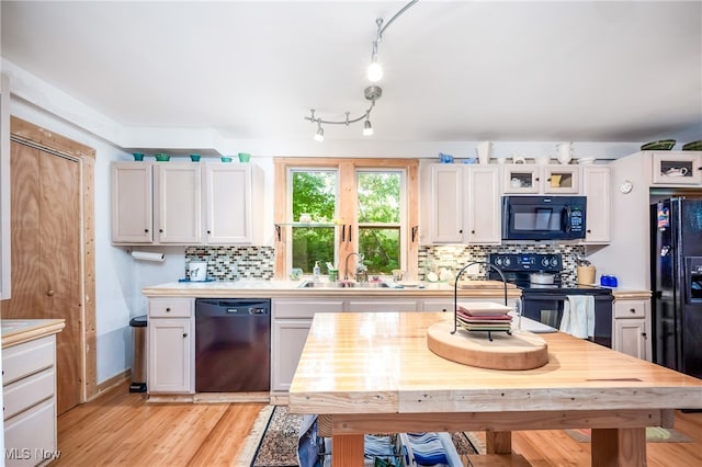 kitchen with decorative backsplash, track lighting, black appliances, and white cabinetry