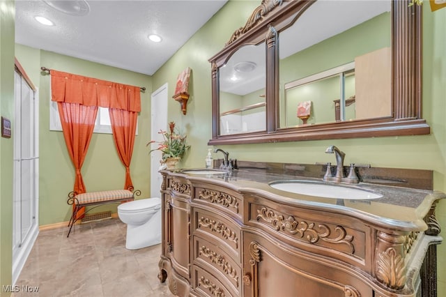 bathroom with vanity, a shower with shower door, toilet, and a textured ceiling