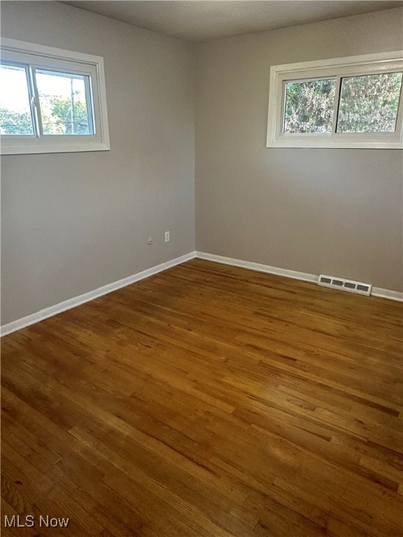 spare room featuring dark hardwood / wood-style floors and plenty of natural light