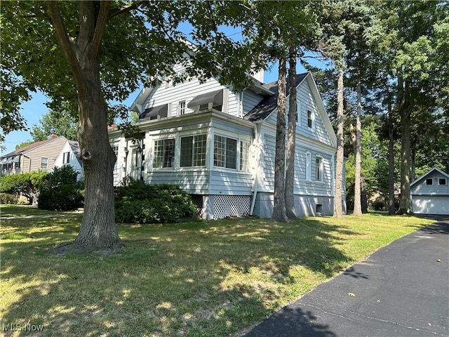 view of front of property featuring a garage, an outbuilding, and a front lawn