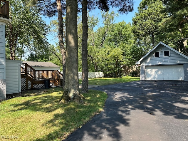 view of yard featuring an outbuilding, a wooden deck, and a garage