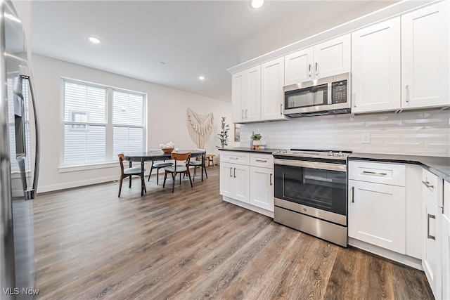 kitchen featuring white cabinets, hardwood / wood-style flooring, appliances with stainless steel finishes, and backsplash